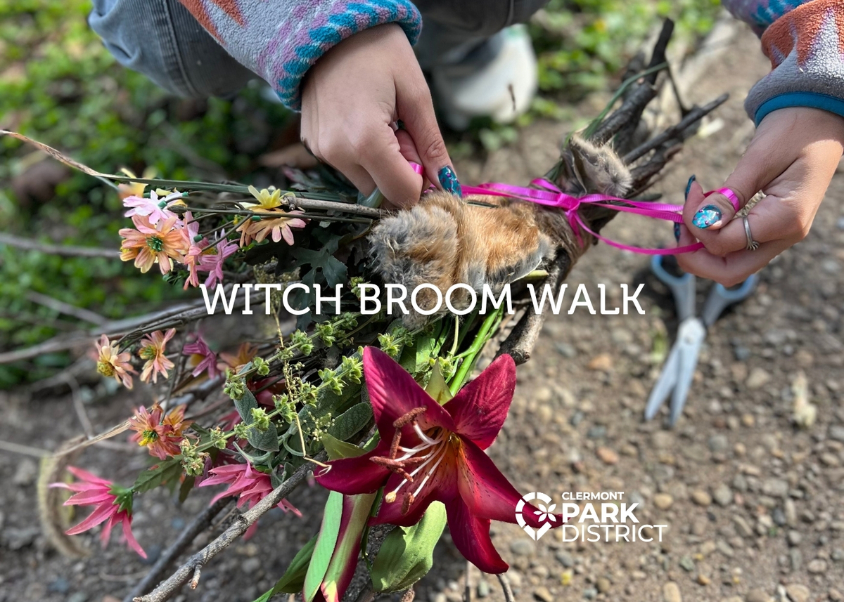 Hands tying a ribbon on a broom of herbs and flowers