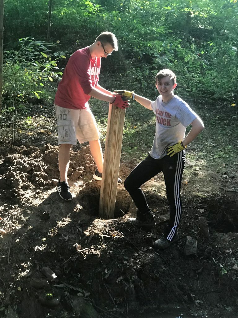 two people putting post in ground